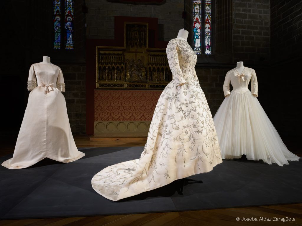 Vestido Shantung marfil y lentejuelas, vestido en raso con abalorios en mangas y vestido en tul con aplicaciones de Cristóbal Balenciaga en la cabecera del refectorio de la catedral de Pamplona.